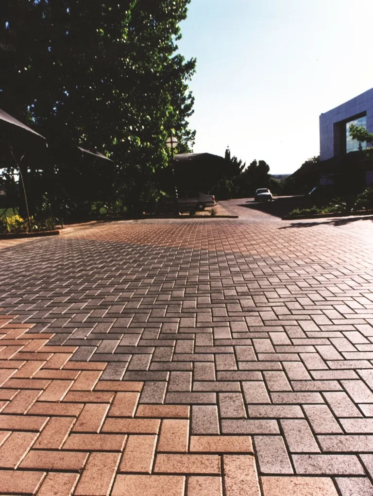 Red and charcoal brick driveway paving beside a face-brick boundary wall