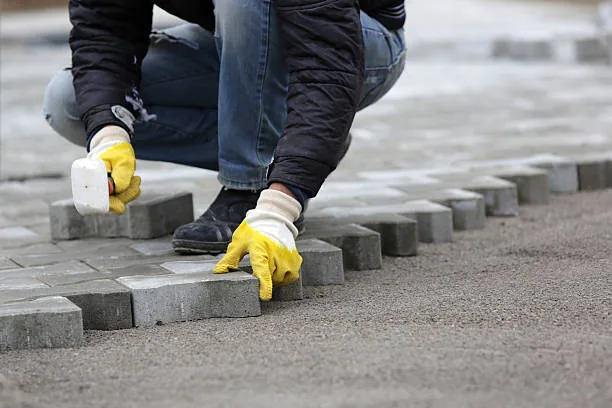 A Rapid Paving installer laying cobble pavers by hand on a Gauteng site