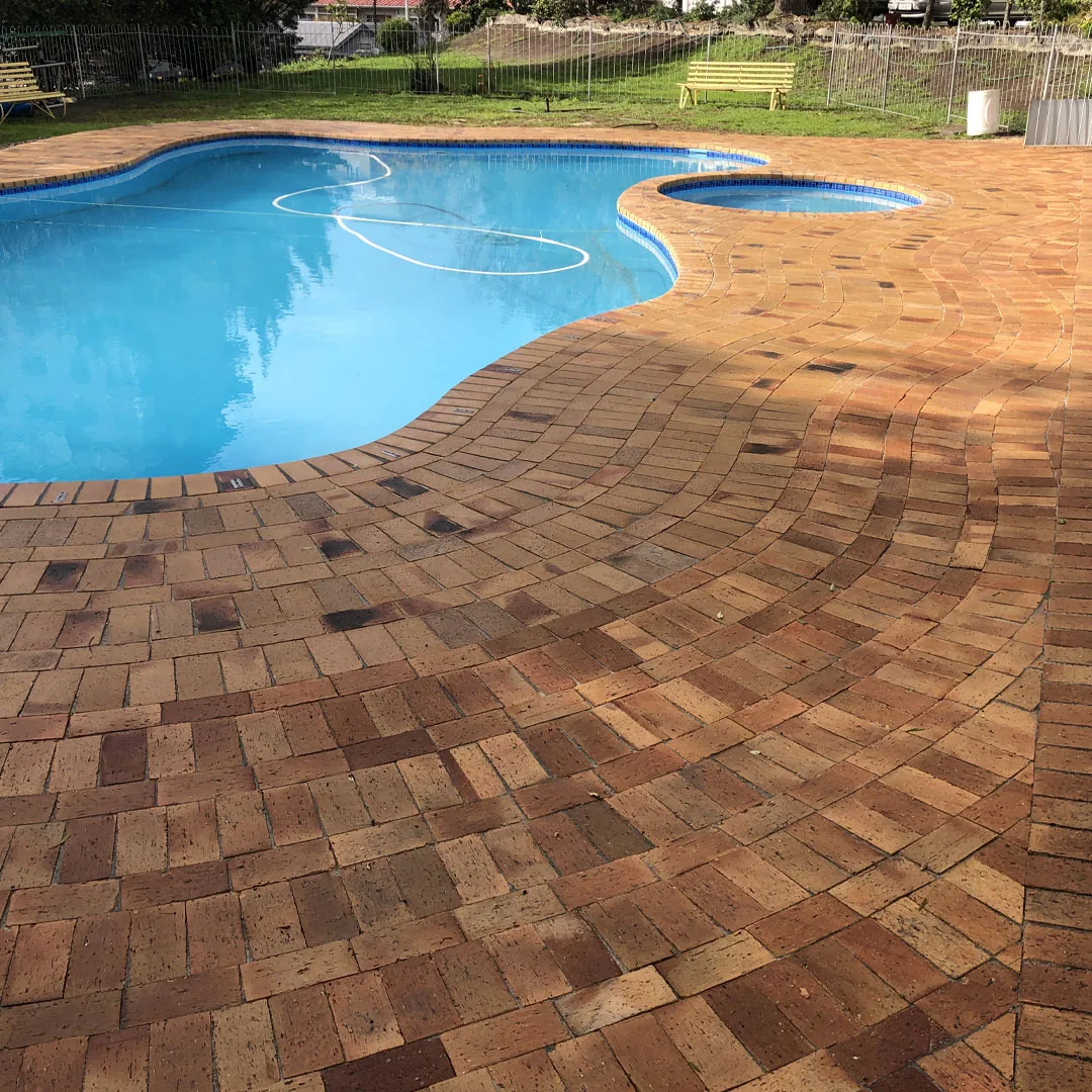 Clay brick pool deck paving surrounding a swimming pool in a residential garden